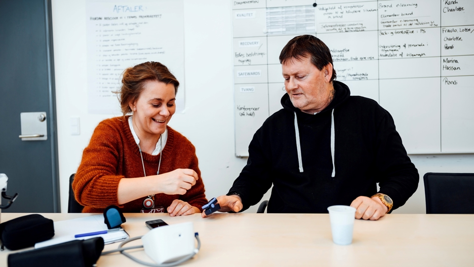 Læge måler puls på patients finger
